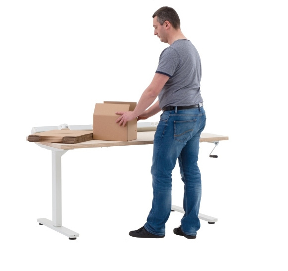 Opérateur préparant des cartons sur un poste de travail réglable en hauteur manuel en position basse Opérateur préparant des cartons sur un poste de travail réglable en hauteur manuel en position basse