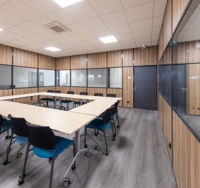 Salle de réunion aménagée à l’aide de cloisons de bureau ainsi que de tables et chaises ergonomiques à roulettes
			