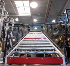 Escalier métallique installé dans une salle de sport pour accéder à une plateforme
			