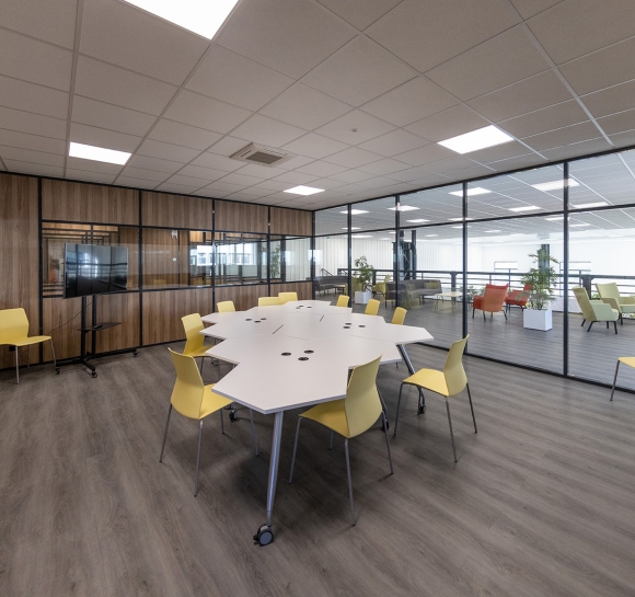 Salle de réunion avec tables et chaises design, installée sur une plateforme de bureaux
		                    