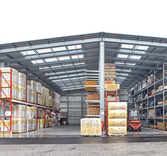 Stockage extérieur de matériaux vue de face, monté avec des racks cantilever équipés d’auvent avec des translucides
													