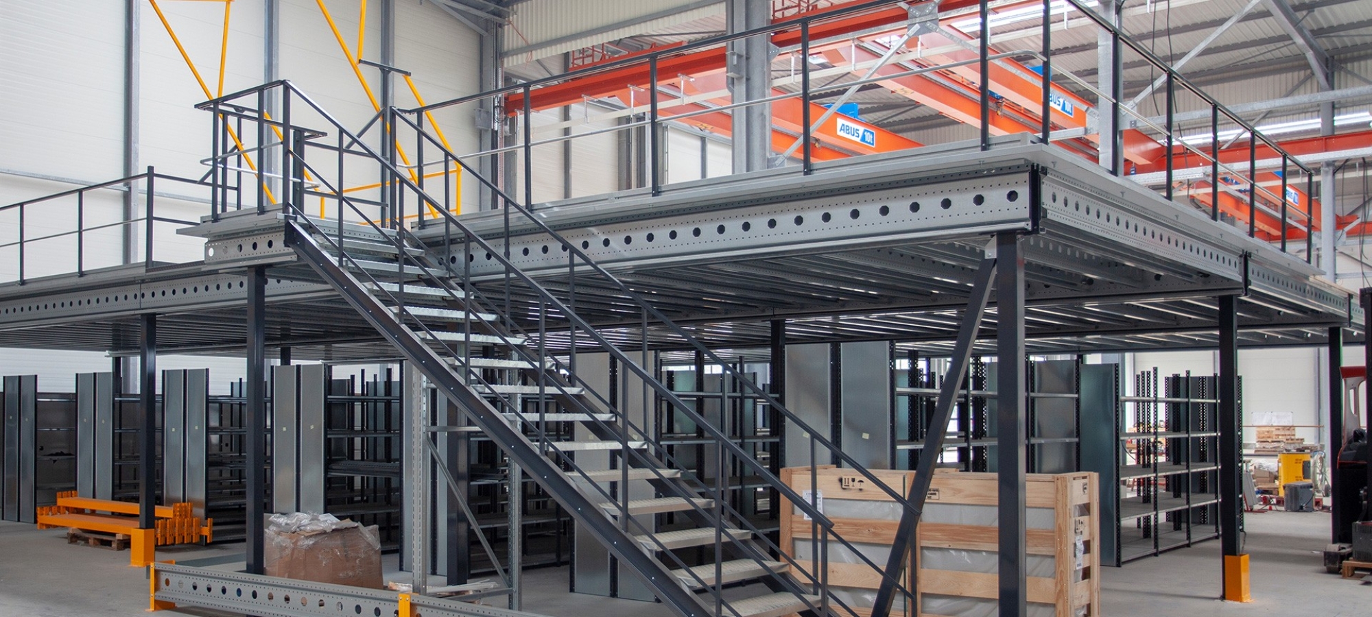 Metalen mezzanine op één niveau met trap en sluisdeur in een magazijn
			                        