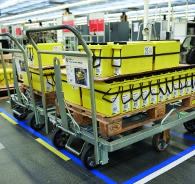 Gemotoriseerde trucks die worden gebruikt om onderdelen op pallets te verplaatsen in een fabriek
			