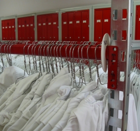 Witte jassen opgeslagen op Prorack+ rekken in een gemeenschappelijke kleedkamer 
			