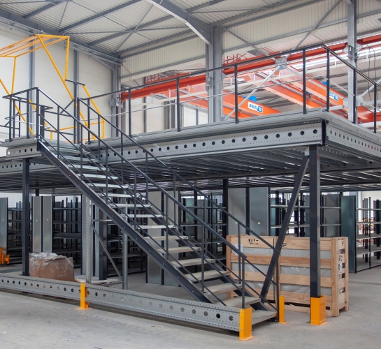 Metalen mezzanine op één niveau met trap en sluisdeur in een magazijn
                
