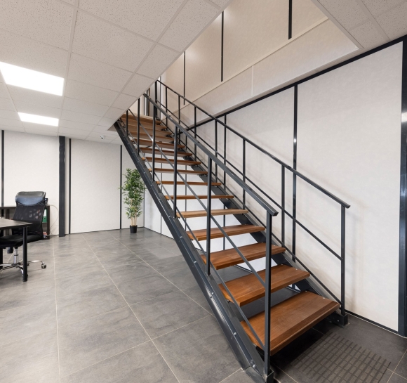 Metalen trap met houten treden geïnstalleerd in een bedrijfspand om toegang te bieden tot de bovenverdieping
		                    